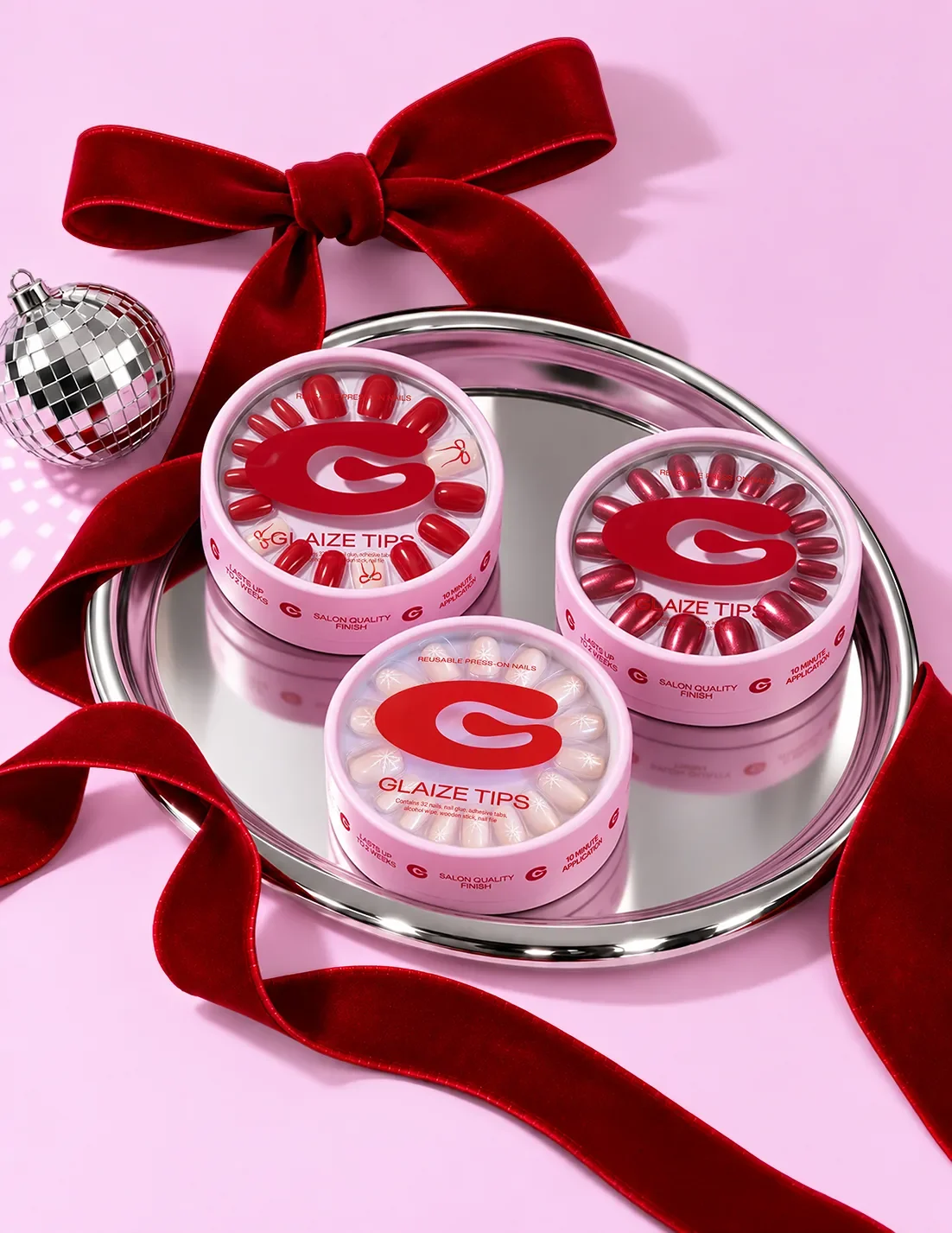 Three Glaize Tips press-on cases on a silver tray tied with a red velvet ribbon