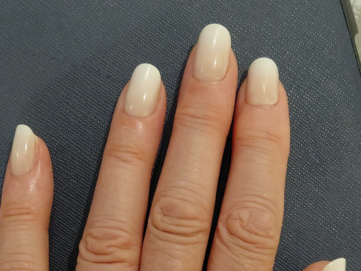 A hand wearing white ombre Glaize Tips press-on nails